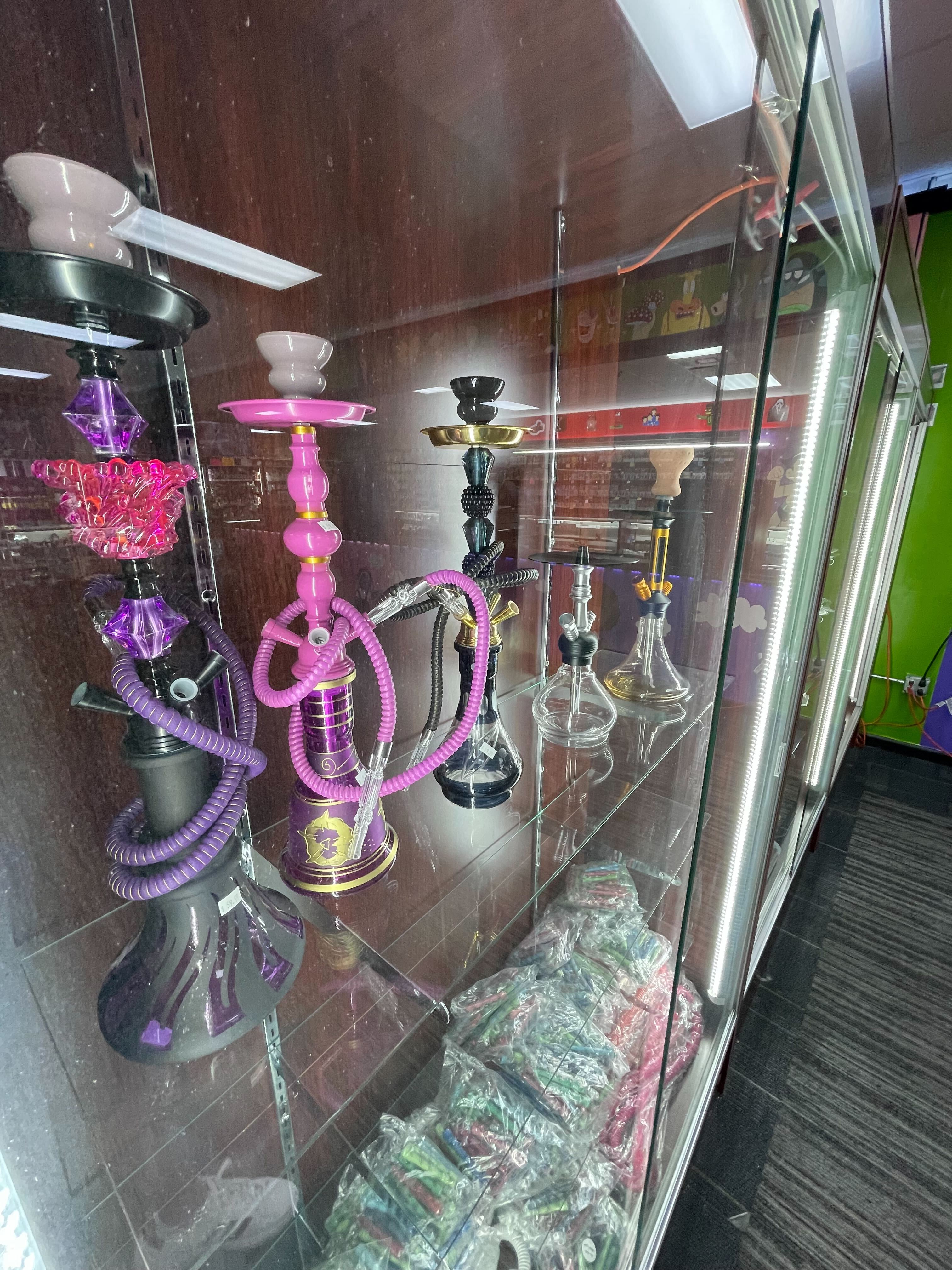Colorful hookah pipes displayed in a glass case at a smoke shop